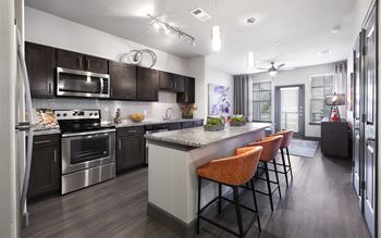 A kitchen with stainless steel appliances and a large island with chairs